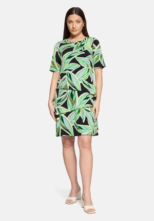 Bloemenjurk met groene en zwarte bladvormen en een gelaagd ontwerp. Korte mouwen en een aansluitend silhouet; gladde, lichte stof.