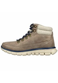 Bota de senderismo de cuero marrón claro con un collar acolchado color crema, cordones azules, ojales dorados y una suela blanca flexible con ranuras texturizadas.
