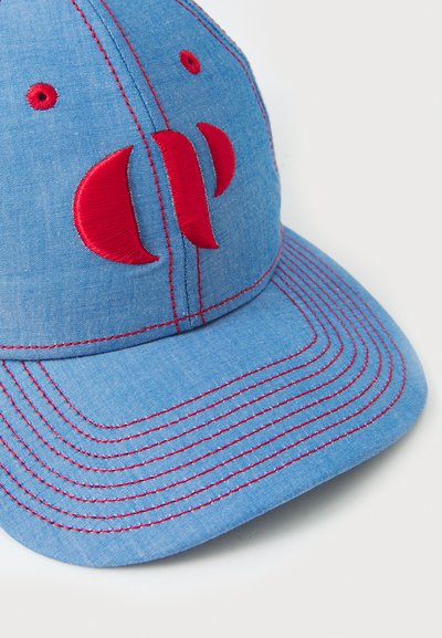 Cappello in denim blu con logo ricamato rosso, cuciture a contrasto, visiera leggermente curva e fori di ventilazione sulla corona.