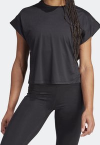 Top atlético negro de manga corta con un ajuste holgado, textura acanalada y escote redondo, combinado con leggings negros a juego.