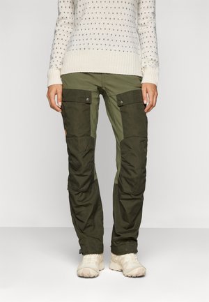 Cargo-broek in donkergroen met lichter groene zijpanelen, voorzien van meerdere zakken met drukknoopsluitingen en een taps toelopende pasvorm.