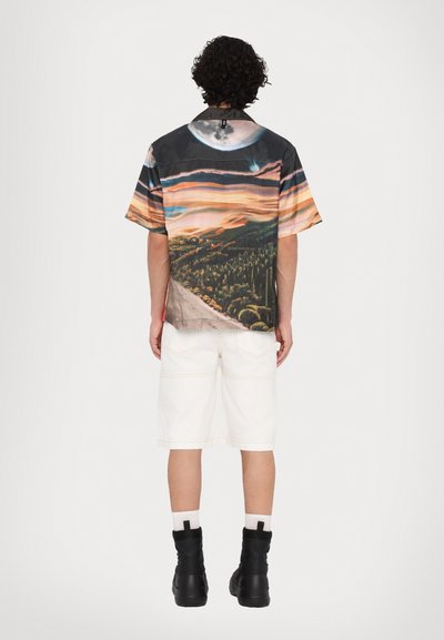 Short-sleeve shirt with a multi-colored landscape print, featuring a dark base, wider sleeves, and a relaxed fit, paired with white shorts and black boots.