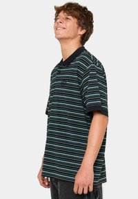 Polo de manga corta en negro con rayas horizontales en azul y verde. Cuenta con un collar clásico y un logotipo bordado en el pecho.
