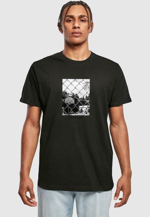 Schwarzes T-Shirt mit einem zentralen Grafikmotiv eines Basketballfeldes hinter einem Maschendrahtzaun, mit der Aufschrift "NICHT NUR EIN SPIEL" darunter.