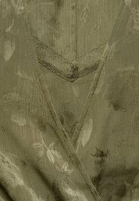 Robe portefeuille verte olive avec un motif floral ; tissu texturé, décolleté en V et délicate dentelle le long de l'encolure.