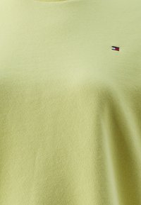 Lichtgroene sweatshirt gemaakt van zachte stof, met een ronde hals en een klein geborduurd logo op de linkerborst. Gladde textuur.