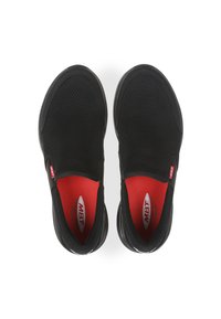 Scarpe da ginnastica nere con tomaia in mesh traspirante, fodera interna rossa, design slip-on e forma minimalista. Presentano il marchio sui lati.