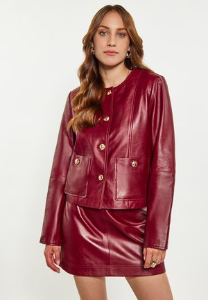 Bordeaux leren jack met gouden knopen, voorzien van een ronde halslijn, twee voorzakken en een cropped ontwerp, gecombineerd met een bijpassende rok.