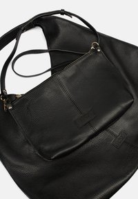 Borsa a mano in pelle nera con finitura testurizzata, un comparto principale e una piccola tasca con zip attaccata con accessori in metallo.