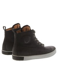 Botines de ante negro con acentos de cuero, punta redonda, ojales de metal y suela de goma con un patrón texturizado en el tacón.