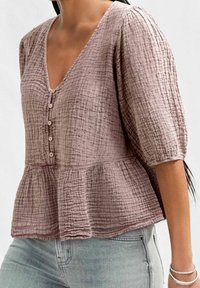 Peplum top in dusty rose, made of textured fabric with a crinkled pattern. Features a V-neck, button closure, and three-quarter sleeves.