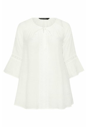 White loose blouse with 3/4 bell sleeves, lace trim on sleeves and front, round neckline, and tie closure at front neck.
