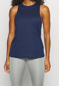Marinblå ärmlös sporttopp med en strukturerad leopardmönstring, rund halsringning och en liten logotyp på övre vänstra bröstet.