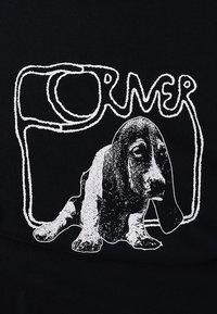 Μαύρο ύφασμα με λευκό γραφικό σχεδιασμό ενός μπάσετ χάουντ και το κείμενο «FORMER» σε μια παιχνιδιάρικη, περιγραμμένη γραμματοσειρά που το περιβάλλει.