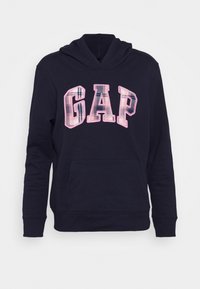 Námořnická mikina s přední kapsou a kapucí na šňůrku. Na hrudi je velké růžové kostkované nápis "GAP". Měkká struktura látky.