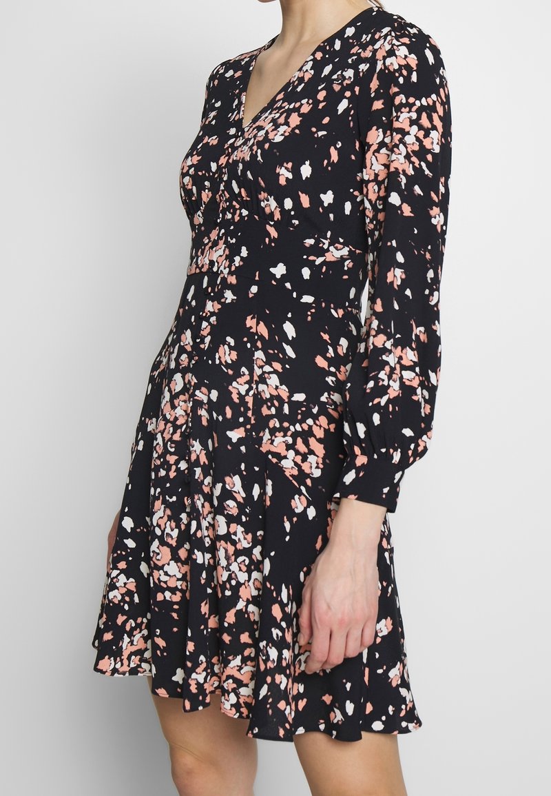 Blommig klänning i lätt material, med svart bakgrund och rosa samt vita splashar, långa ärmar och utsvängd nederkant.