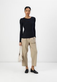 TUME SININE PIKKVARU KÜÜNED, BEIGE ÜHENDATUD PÜKSID, MUSTAD LOAFERID JA HELE BEIGE KOTI, VALGE TAUSTAL.
