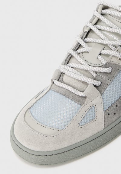 Baskets grises claires avec des panneaux en daim et en mesh, dotées de lacets blancs, d'un bout arrondi et d'une semelle en caoutchouc texturée. Construites avec des accents en bleu.