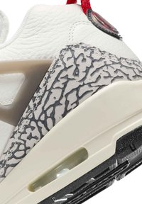 Hvide lædersneakers med grå teksturerede detaljer, gennemsigtig luftdæmper og rød træksløjfe. Svartr gummisål med detaljeret slidbane.