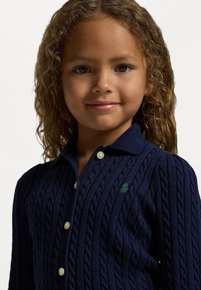 Cardigã de malha canelada azul-marinho com gola de colarinho, apresentando botões em contraste e um pequeno bordado de logótipo verde no peito.