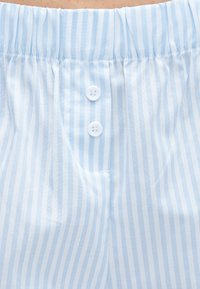 Ύφασμα με κάθετες ρίγες σε ανοιχτό μπλε και λευκό χρώμα, με δύο λευκά κουμπιά και ελαστική μέση σε ένδυμα.