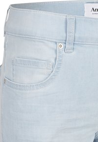 Světle modré džínové šortky s hladkou texturou, vybavené přední kapsou, kovovými doplňky a viditelným prošitím podél švů.