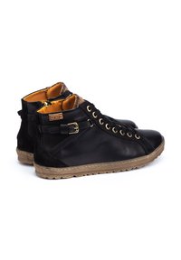 Scarpe in pelle nera alta con occhielli dorati, interno beige e suola in gomma. Presentano una zip laterale e dettagli con cintura.