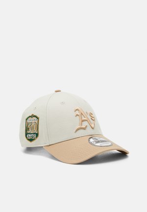 Beige cap with a tan brim, featuring an embroidered "A's" logo and a green and gold patch noting "Oakland 50 Athletics 1968-2018."