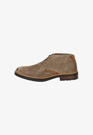 Stivaletto in suede taupe con dettagli in cuoio marrone, punta arrotondata e cuciture a contrasto. Presenta cinque fori per i lacci e una suola in gomma resistente.