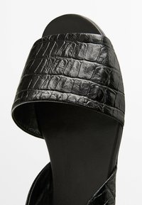 Schwarze Sandalen mit offenem Zehenbereich, ausgestattet mit einem strukturierten Krokodilleder-Design, glatter schwarzer Sohle und einem breiten Riemen für einen sicheren Sitz.