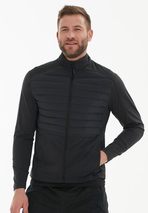 Schwarze Jacke mit einem Reißverschluss vorne, ausgestattet mit einem gesteppten Einsatz über der Brust und glatten Ärmeln. Entworfen mit einem hohen Kragen und einer taillierten Silhouette.