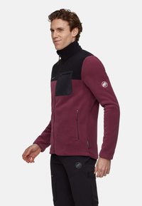 Kurtka polarowa w kolorze bordowym z czarnymi akcentami. Posiada kieszenie na zamek błyskawiczny oraz wysoki kołnierz. Miękka w dotyku, dopasowany krój.