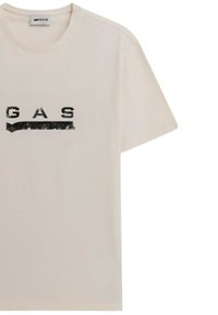 T-shirt in cotone beige con collo rotondo, maniche corte e una stampa grafica nera della parola "GAS" sul petto.