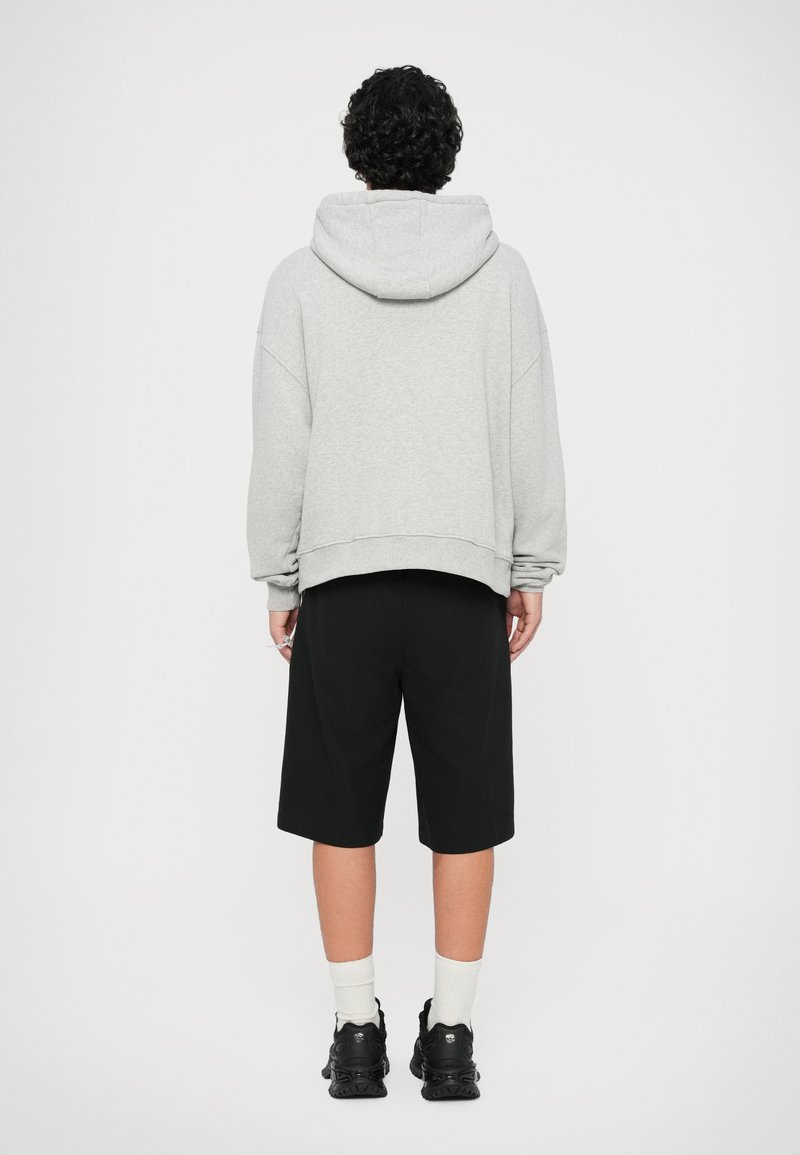 Gray hooded sweatshirt with dropped shoulders paired with black shorts and black sneakers, featuring white ankle socks. Simple, casual design.