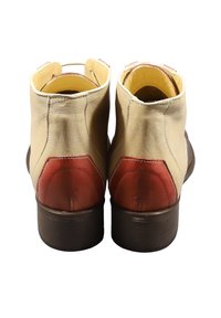 Stivali alla caviglia beige in pelle con dettagli di tacco rosso, punta arrotondata e suola bassa marrone. Texture liscia, cuciture minime.