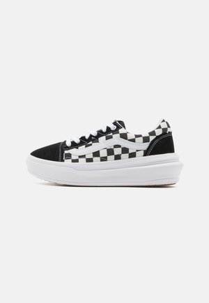 Scarpe da ginnastica in tela a scacchi bianchi e neri con la punta in suede nero a contrasto e suola in gomma bianca. Presentano lacci bianchi e un logo laterale.