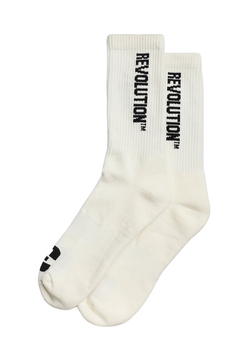 Witte katoenen sokken met ribbelstructuur, featuring zwart "REVOLUTION" tekst verticaal gedrukt aan de zijkanten en een zwart grafisch ontwerp aan de onderkant.