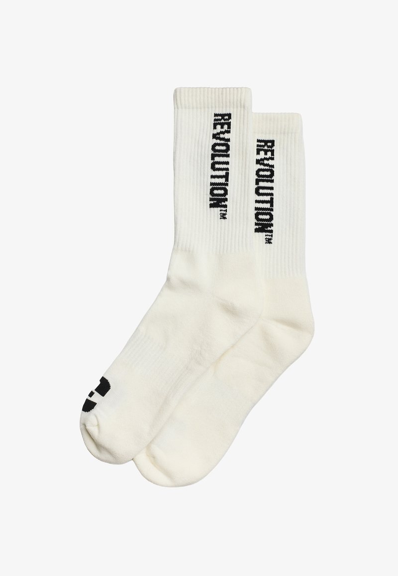 Witte katoenen sokken met ribbelstructuur, featuring zwart "REVOLUTION" tekst verticaal gedrukt aan de zijkanten en een zwart grafisch ontwerp aan de onderkant.