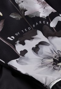 Virágmintás szövet fehér és szürke árnyalatokban, fekete alapon; fehér szöveggel "b by Ted Baker" logóval. Sima tapintású.