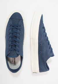 Baskets en daim bleu avec semelles en caoutchouc blanches, bout rond et design à lacets. Comprennent des trous de ventilation et un logo sur la semelle intérieure.