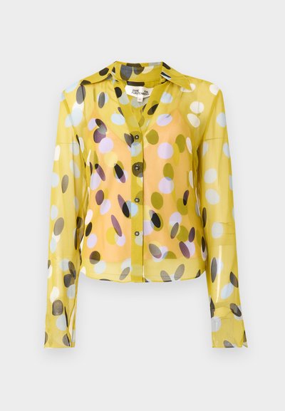 Κίτρινο διάφανο πουκάμισο με μακριά μανίκια, κουμπιά μπροστά, διακοσμημένο με πολύχρωμα κυκλικά σχέδια σε διάφορα μεγέθη και κλασικό γιακά.