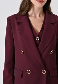 Bordeaux dubbelzijdige blazer met verticale strepen, gouden ronde hardware en een puntige revers; heeft een voorzak.