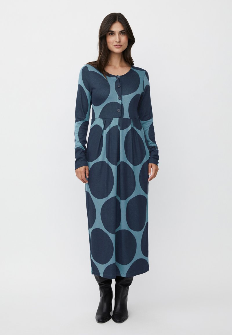 Abito da donna a maniche lunghe, con bottoni, di colore teal con grandi cerchi navy, caratterizzato da una gonna arricciata e un collo rotondo. Tessuto morbido ed elastico.