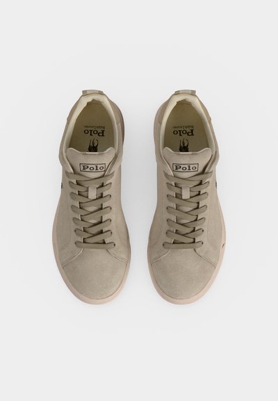 Μπεζ γυναικεία sneakers Polo Ralph Lauren από σουέντ με κορδόνια, στρογγυλεμένες μύτες και λογότυπο στη γλώσσα, τοποθετημένα δίπλα δίπλα σε λευκό φόντο.