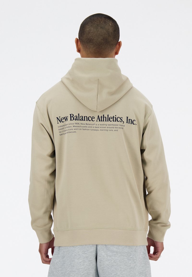 Béžová mikina s kapucí a volným střihem, na zádech velké logo a nápis. Měkká látka, dlouhé rukávy a žebrované manžety.