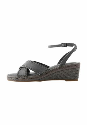 Sandale wedge gri cu curele în cruce, realizate dintr-un material texturat. Talpa prezintă detalii împletite și o ușoară curbură pentru suport.