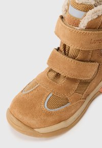 Tan ruskind og mesh støvle med Velcro-stropper, rund tå, tekstureret overdel og reflekterende detaljer. Velegnet til udendørs brug.