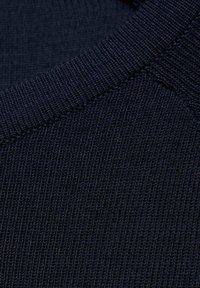 Gros plan d’un tissu tricoté bleu foncé montrant une texture côtelée détaillée et des coutures.