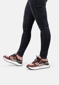 Sportliche Sneaker in Bordeaux, Schwarz und Blush-Pink mit Mesh- und Wildleder-Texturen, ausgestattet mit einer weißen Zwischensohle und schwarzen Schnürsenkeln.