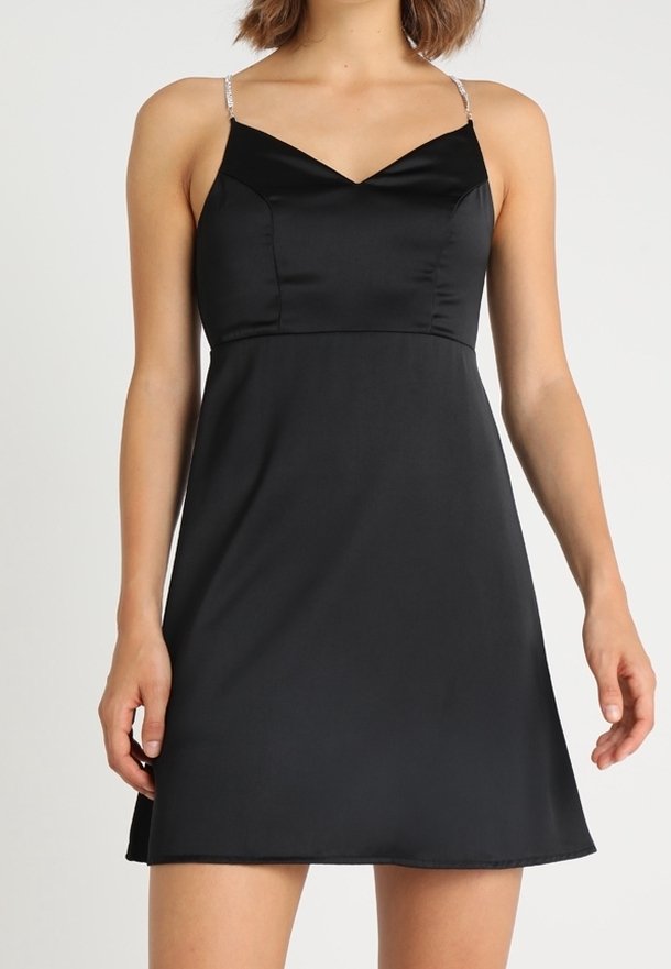 Robe en satin noir avec un corsage ajusté, un décolleté en V et une jupe évasée. Comprend des bretelles fines et scintillantes pour plus de détails.